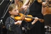 talented young woman playing violin in a concert hall